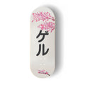 A Yurt fingerboard deck consisting of a 5-ply maple deck with a colourful Real Wear graphic design featuring pink cherry blossom illustrations on a white background and the black Japanese katakana characters 'ゲル' meaning Geru or Yurt, printed vertically in the centre. 