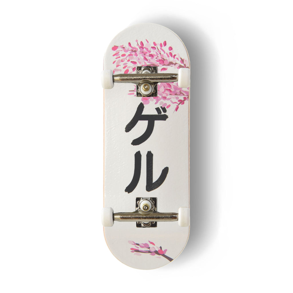 A Yurt fingerboard complete with silver trucks and white wheels, consisting of a 5-ply maple deck with a colourful Real Wear graphic design featuring pink cherry blossom illustrations on a white background and the black Japanese katakana characters 'ゲル' meaning Geru or Yurt, printed vertically in the centre. 