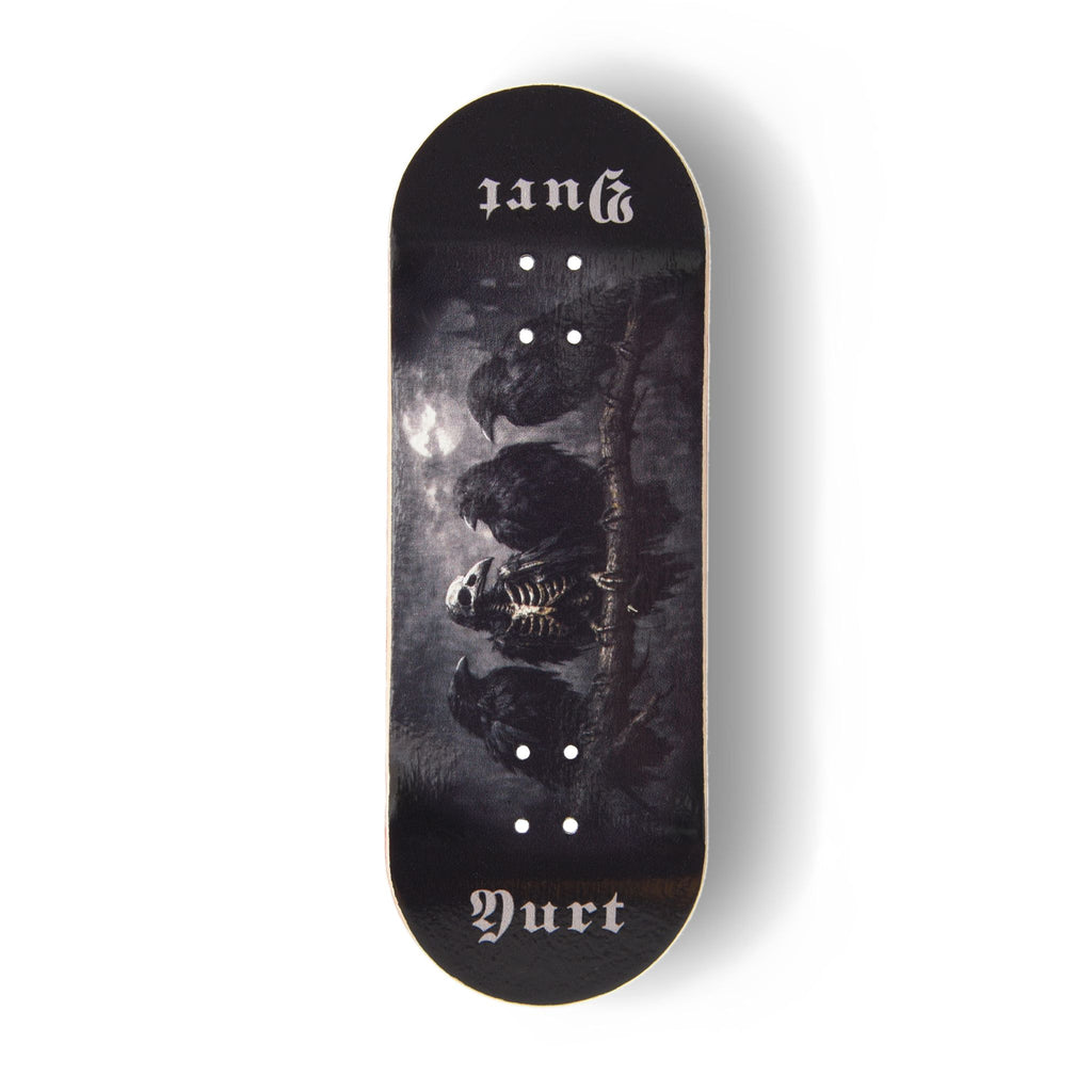 A Yurt fingerboard deck  consisting of a 5-ply maple deck with a Real Wear graphic with a dark gothic design featuring four crows and the word 'Yurt' in a gothic font on the tail. The board has a black background with a detailed print of a skeletal crow under a cloudy sky.