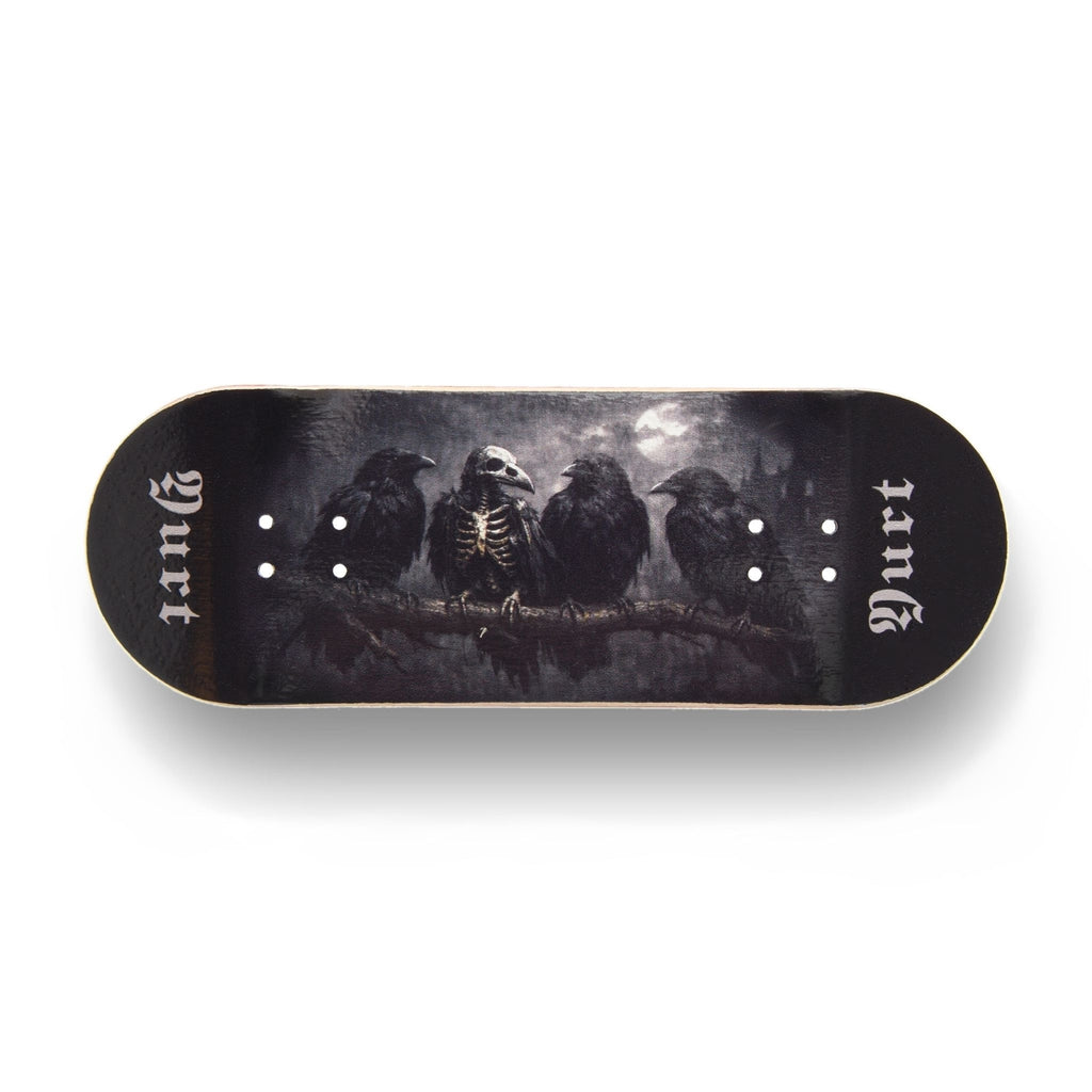A Yurt fingerboard consisting of a 5-ply maple deck with a Real Wear graphic with a dark gothic design featuring four crows and the word 'Yurt' in a gothic font on the tail. The board has a black background with a detailed print of a skeletal crow under a cloudy sky. Horizontal view. 