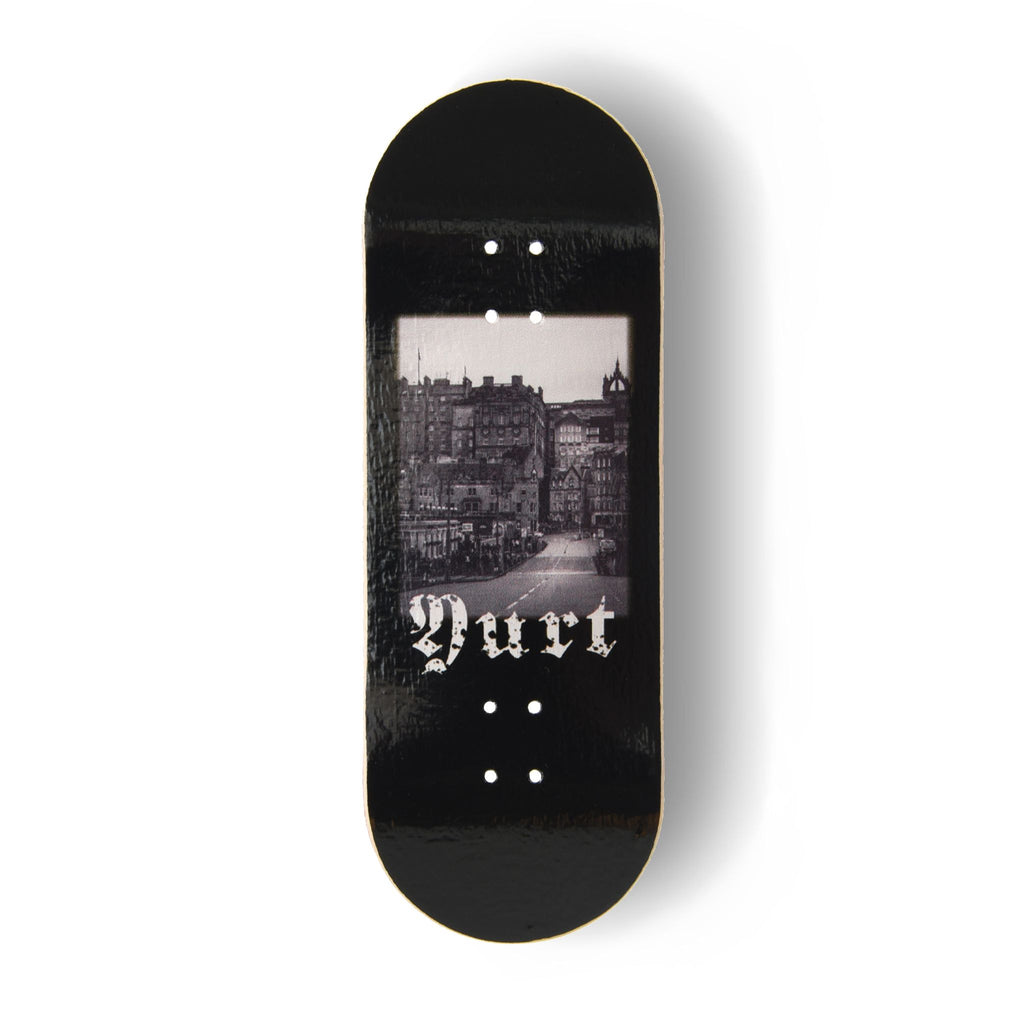 A Yurt fingerboard deck  consisting of a 5-ply maple deck with a Real Wear graphic design with a black and white view of Edinburgh and gothic writing spelling the word 'Yurt'. 