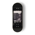 A Yurt fingerboard deck  consisting of a 5-ply maple deck with a Real Wear graphic design with a black and white view of Edinburgh and gothic writing spelling the word 'Yurt'. 