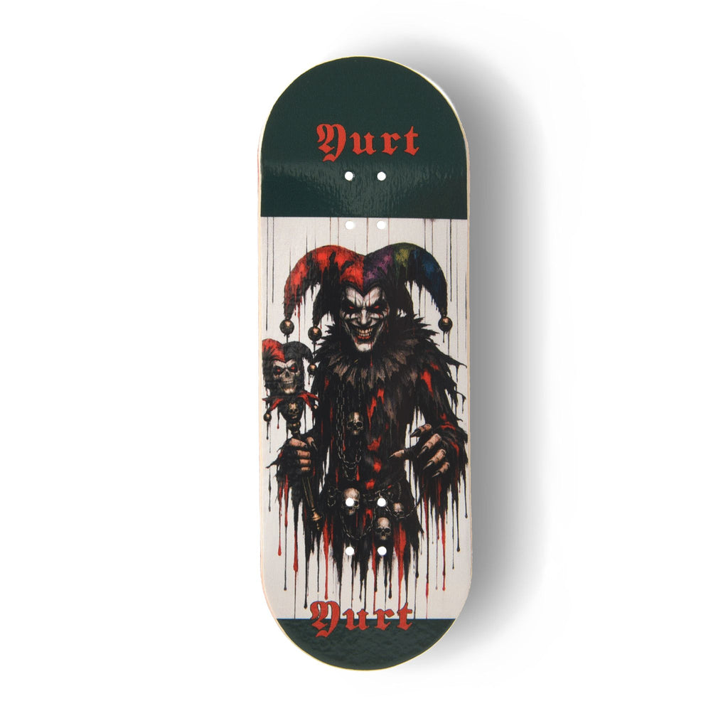 A Yurt fingerboard  deck consisting of a 5-ply maple deck with a colourful Real Wear graphic design featuring a dark, horror-themed jester graphic on a white background, with dark green ends and the word 'Yurt' printed in red gothic lettering.