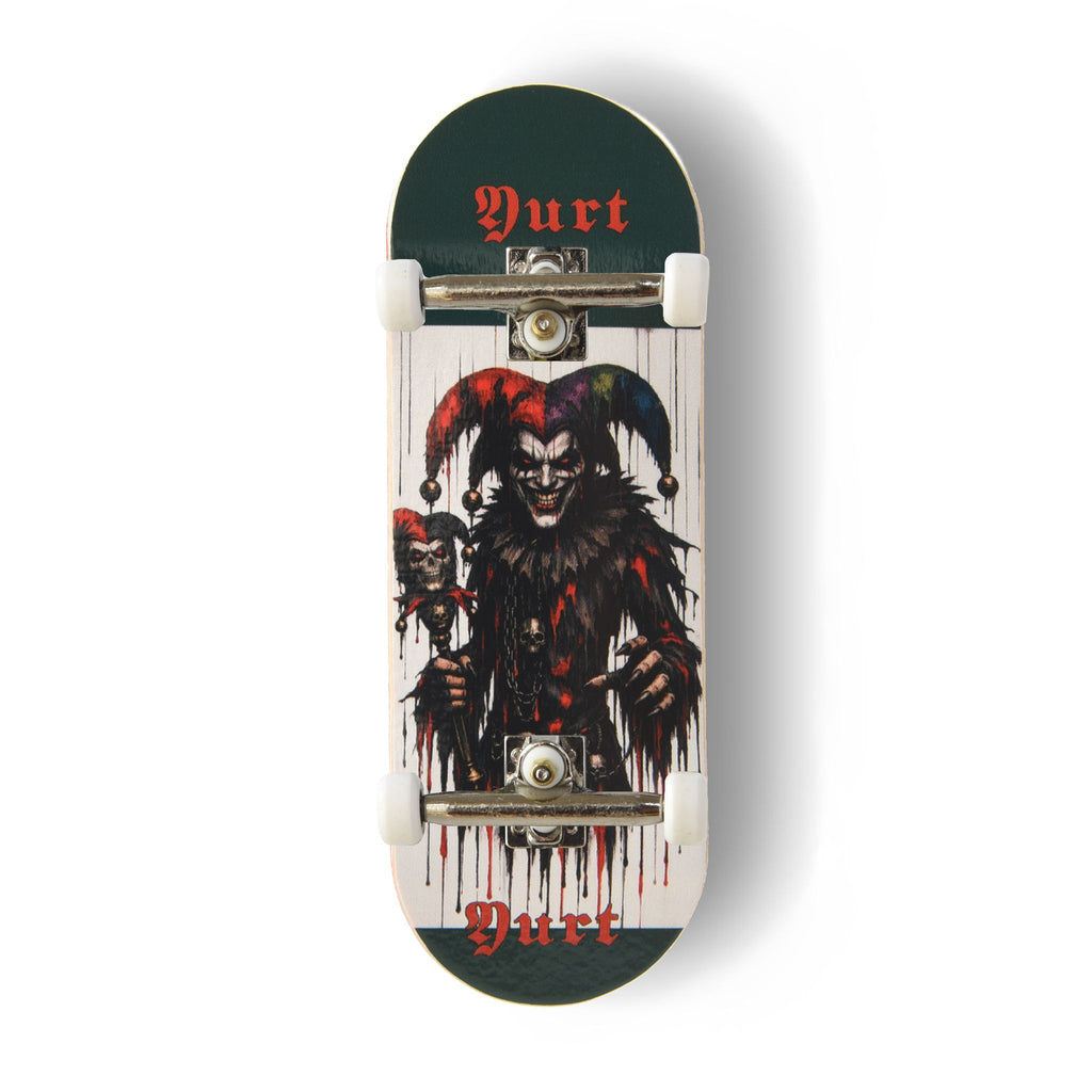 A Yurt fingerboard complete with silver trucks and white wheels, consisting of a 5-ply maple deck with a colourful Real Wear graphic design featuring a dark, horror-themed jester graphic on a white background, with dark green ends and the word 'Yurt' printed in red gothic lettering.